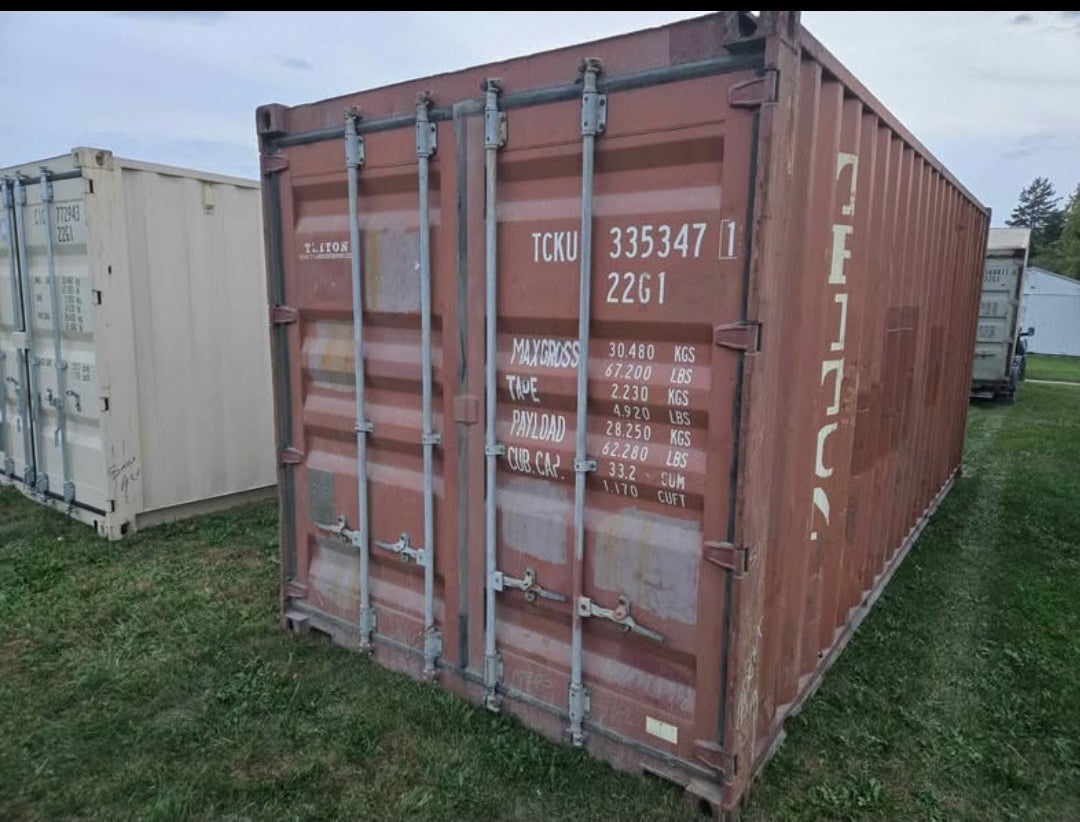Red shipping container with visible branding on a grassy area